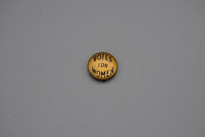 round, gold button with text "Votes for Women"